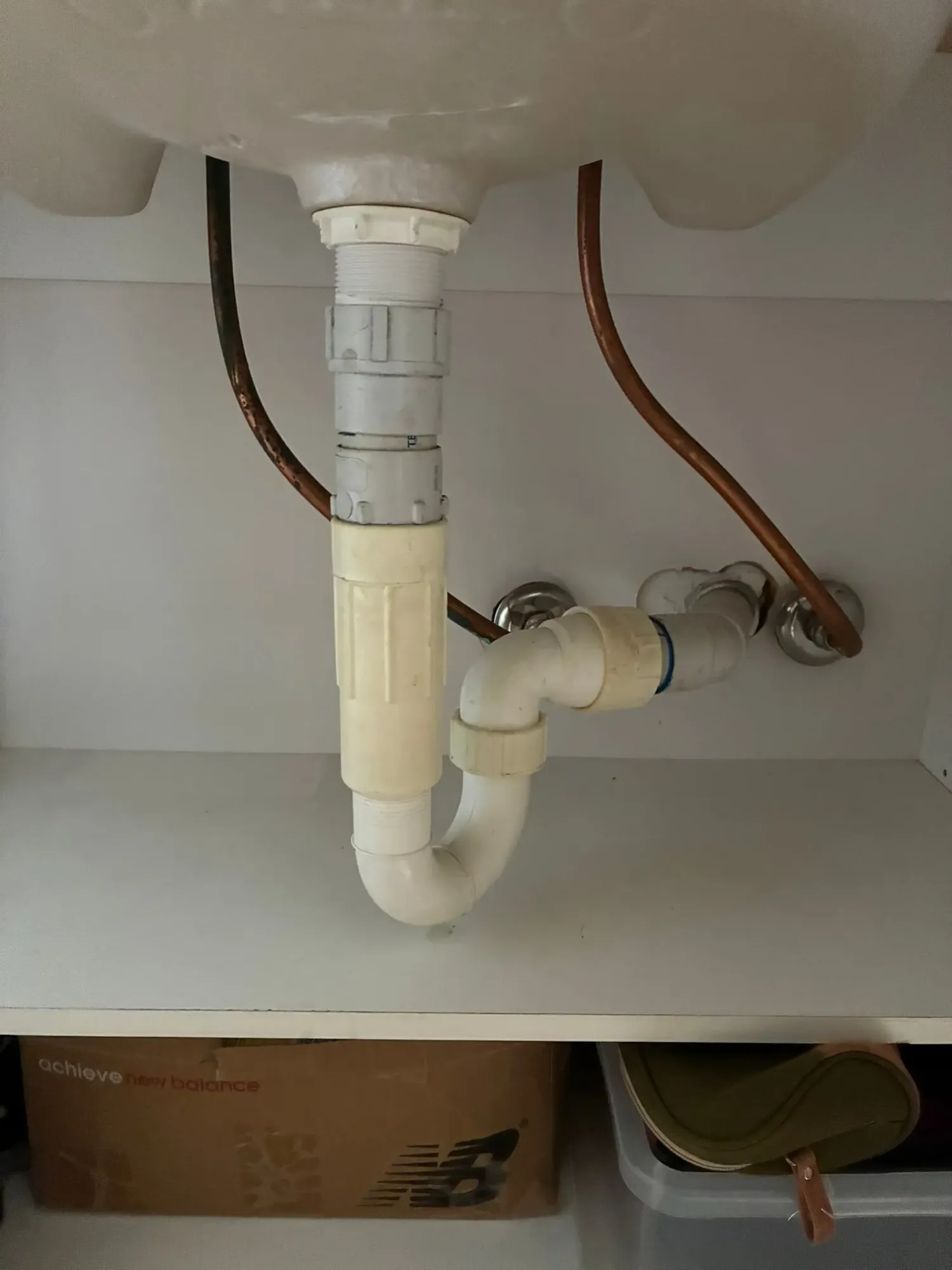 Before: old rigid copper pipes with corrosion under a basin